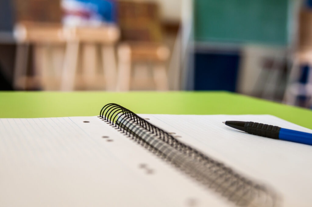 Close-up of a notebook and pen on a classroom desk, representing the flexibility of applying for Matric through distance learning.