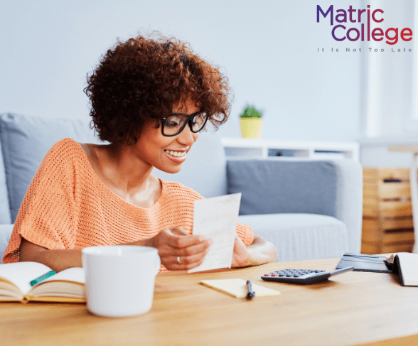 Smiling woman reviewing documents at home with a calculator and notebook, representing one of the many practical Reasons to Choose ICB for your studies.