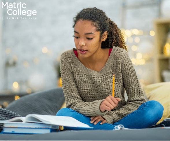 A student studying on a couch with books and notes, preparing for exams as part of her Matric Equivalent Courses through distance learning.