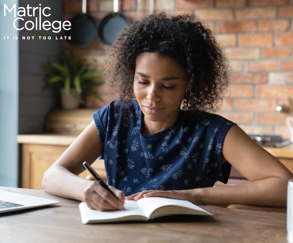 A focused young woman writes in a notebook at home, representing dedicated study efforts—highlighting "Second Chance Matric: Why It Is So Important".