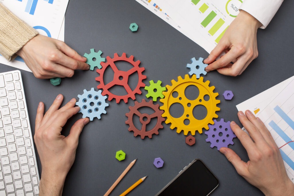 Team members connecting colourful gears to show how you can identify skills gaps in a workplace setting.